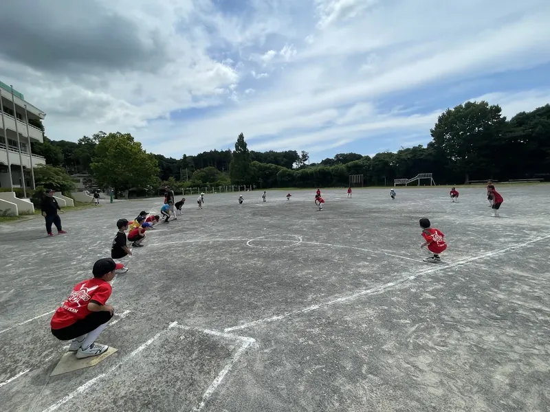 校庭で輪になって準備体操をする子どもたち