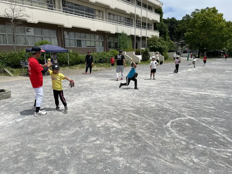 コーチと一緒にボールを投げる練習をする子どもたち