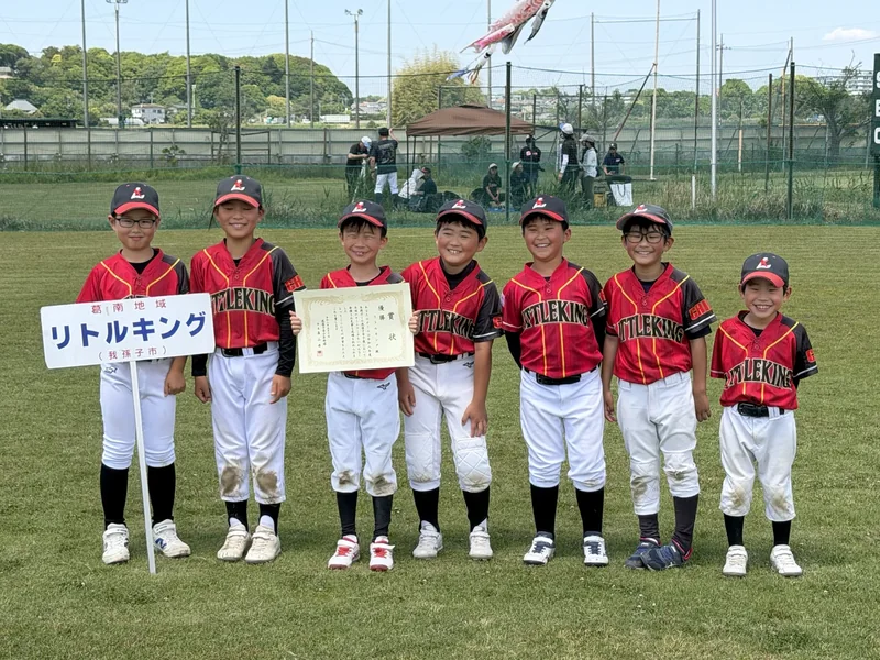 賞状とリトルキングの看板を持ち、笑顔で並ぶ選手たち